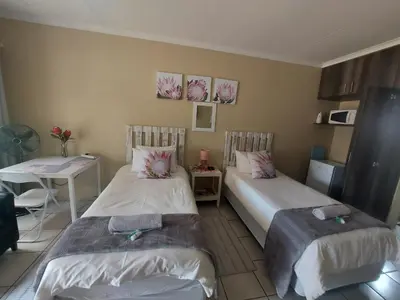 a room with two beds and a table and a table at DeLutz Overnight Accommodation Room 2 in Polokwane