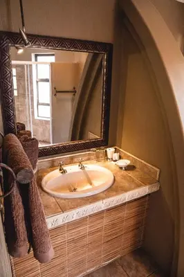 a bathroom with a sink and a large mirror at Bass Lake Country Lodge in Pretoria
