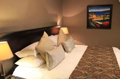 a bedroom with a bed with white sheets and pillows at Bass Lake Country Lodge in Pretoria