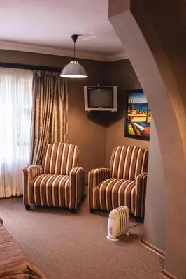 a living room with two chairs and a tv at Bass Lake Country Lodge in Pretoria