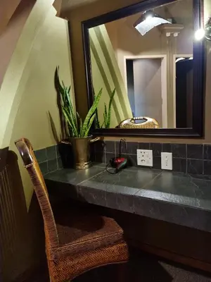 a bathroom sink with a mirror and a chair at Bass Lake Country Lodge in Pretoria