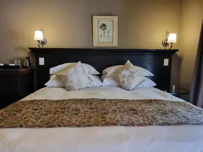 a large bed with white sheets and pillows at Bass Lake Country Lodge in Pretoria