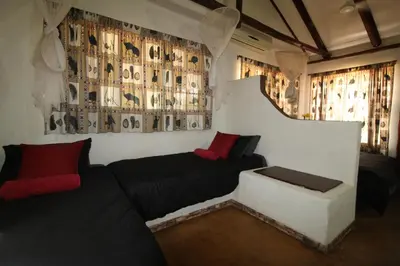 a room with a bed and a couch and curtains at Kiburi Cottage @ Kruger in Marloth Park