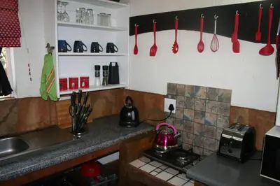 a kitchen with red utensils hanging on the wall at Kiburi Cottage @ Kruger in Marloth Park