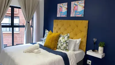 a blue bedroom with a bed with a yellow headboard at The Blyde - Unit 1136 in Pretoria