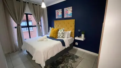 a bedroom with a bed with yellow and blue walls at The Blyde - Unit 1136 in Pretoria