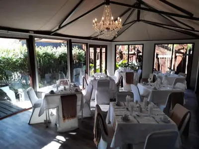 a restaurant with white tables and chairs and a chandelier at Vista ORT in Kempton Park