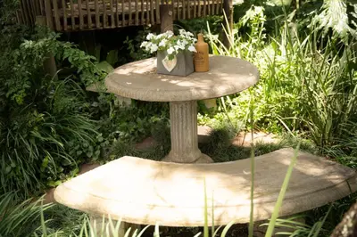 a stone table with flowers on it in a garden at L'anda Guesthouse & self catering in Middelburg