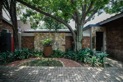a brick house with a tree in the yard at L'anda Guesthouse & self catering in Middelburg
