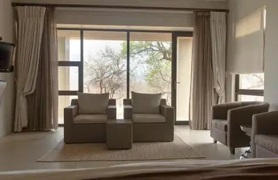 a living room with a couch and a large window at Legend Golf and Safari Resort in Sterkrivier