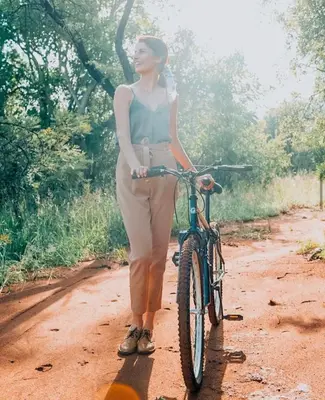 a woman standing next to a bike on a dirt road at Legend Golf and Safari Resort in Sterkrivier