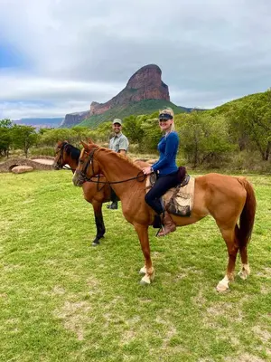 a man and a woman riding on horses in a field at Legend Golf and Safari Resort in Sterkrivier
