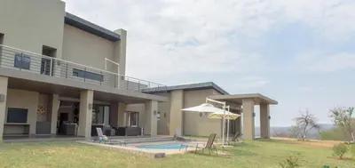 a house with a swimming pool and an umbrella at Legend Golf and Safari Resort in Sterkrivier
