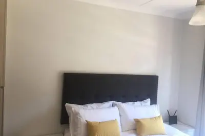 a bed with a black headboard and some pillows at THE BLYDE CRYSTAL LAGOON BEACH PRETORIA in Pretoria