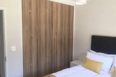 a wooden cabinet in a bedroom with a bed at THE BLYDE CRYSTAL LAGOON BEACH PRETORIA in Pretoria