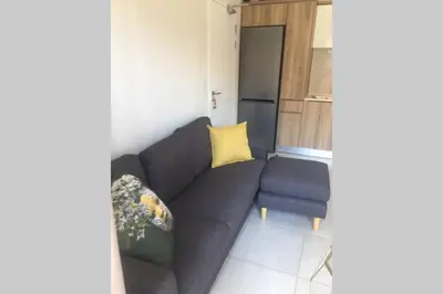 a living room with a gray couch and a yellow pillow at THE BLYDE CRYSTAL LAGOON BEACH PRETORIA in Pretoria