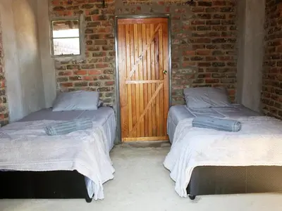 two beds in a room with a wooden door at Wildnut Lodge and Game Farm in Louis Trichardt