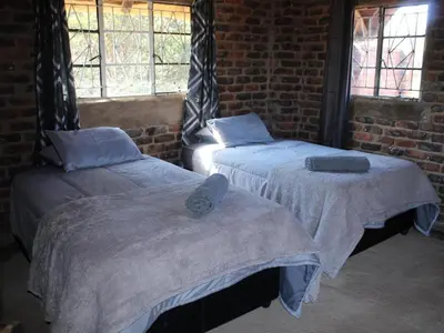 two beds in a room with a brick wall at Wildnut Lodge and Game Farm in Louis Trichardt