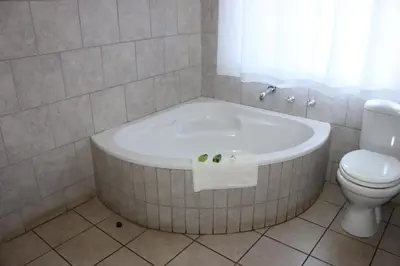 a bathroom with a bath tub and a toilet at El Palmar Guesthouse in Groblersdal