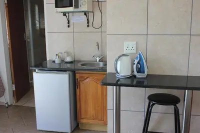 a small kitchen with a sink and a counter with a microwave at El Palmar Guesthouse in Groblersdal