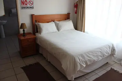 a bedroom with a large white bed and a window at El Palmar Guesthouse in Groblersdal
