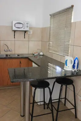 a kitchen with a counter and two stools in it at El Palmar Guesthouse in Groblersdal