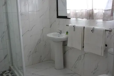 a white bathroom with a sink and a mirror at El Palmar Guesthouse in Groblersdal