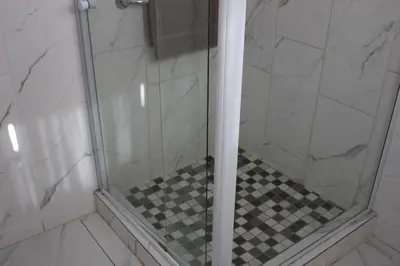 a shower with a black and white checkered floor at El Palmar Guesthouse in Groblersdal