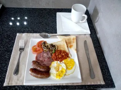 a plate of breakfast food with sausage eggs bread and a cup of coffee at The Royal Prime Guest Lodge in Centurion