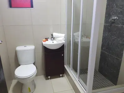 a bathroom with a toilet and a shower and a sink at The Royal Prime Guest Lodge in Centurion
