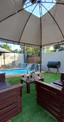 a patio with a table and an umbrella at The Royal Prime Guest Lodge in Centurion