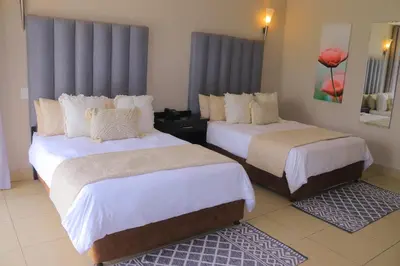 a hotel room with two beds with white sheets at Oasis Hotel in Mokopane