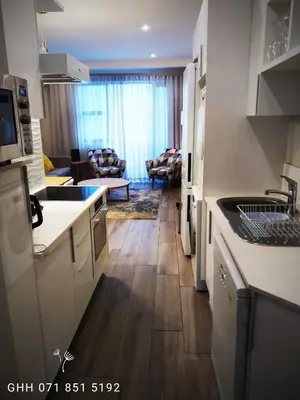 a kitchen with white cabinets and a living room at Regency Apartment in Pretoria