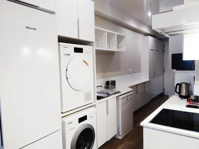 a white kitchen with a washer and dryer at Regency Apartment in Pretoria