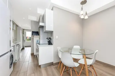 a kitchen with a glass table and white cabinets at Regency Apartment in Pretoria