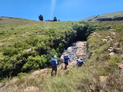 a group of three people walking down a hill at Schaefers' Halt in Dullstroom