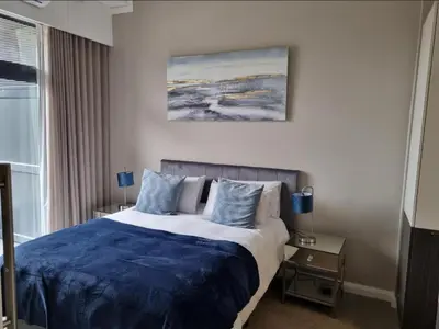 a bedroom with a bed with a blue comforter at Menlyn Maine Apartments in Pretoria