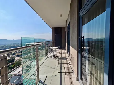 a balcony with chairs and tables on a building at Menlyn Maine Apartments in Pretoria