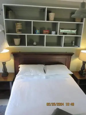 a bedroom with a bed with two lamps and shelves at Beni Apartment in Pretoria
