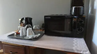 a kitchen counter with a microwave and a tray with cups at Beni Apartment in Pretoria