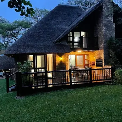 a house with a thatched roof and a wooden fence at INYAMATANE LUXURY LODGES at Kruger Park Lodge in Hazyview