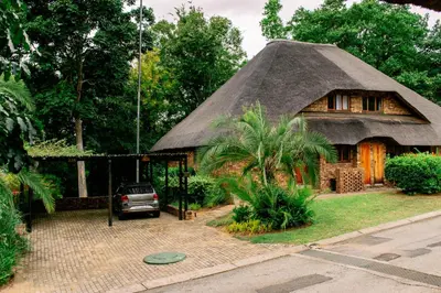 a thatch roofed house with a car parked in front at INYAMATANE LUXURY LODGES at Kruger Park Lodge in Hazyview