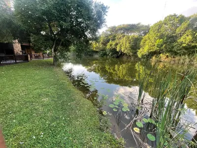 a river with trees and grass next to a field at INYAMATANE LUXURY LODGES at Kruger Park Lodge in Hazyview