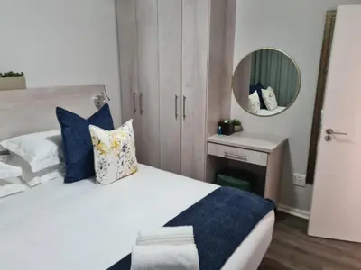 a bedroom with a bed with blue pillows and a mirror at Villa Casa Lifestyle in Nelspruit
