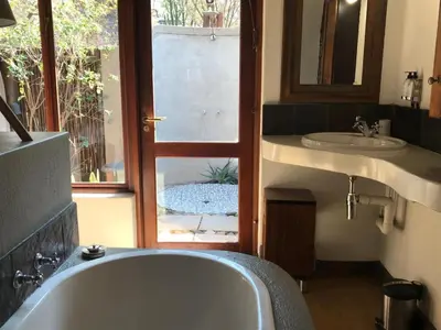 a bathroom with a tub and a sink and a window at 11 Raptors Lodge in Hoedspruit