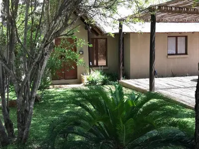 a house with a green yard with a tree at 11 Raptors Lodge in Hoedspruit