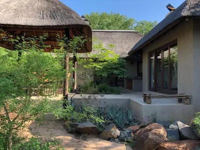 a house with a thatch roof and a garden at 11 Raptors Lodge in Hoedspruit