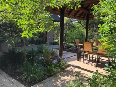 a patio with a table and chairs under a pergola at 11 Raptors Lodge in Hoedspruit
