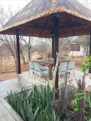 a wooden gazebo with chairs and a table at 11 Raptors Lodge in Hoedspruit