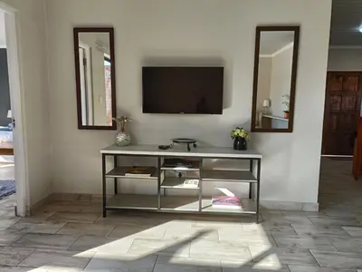 a living room with a television on a wall at Sedgefield Lodge in Witbank